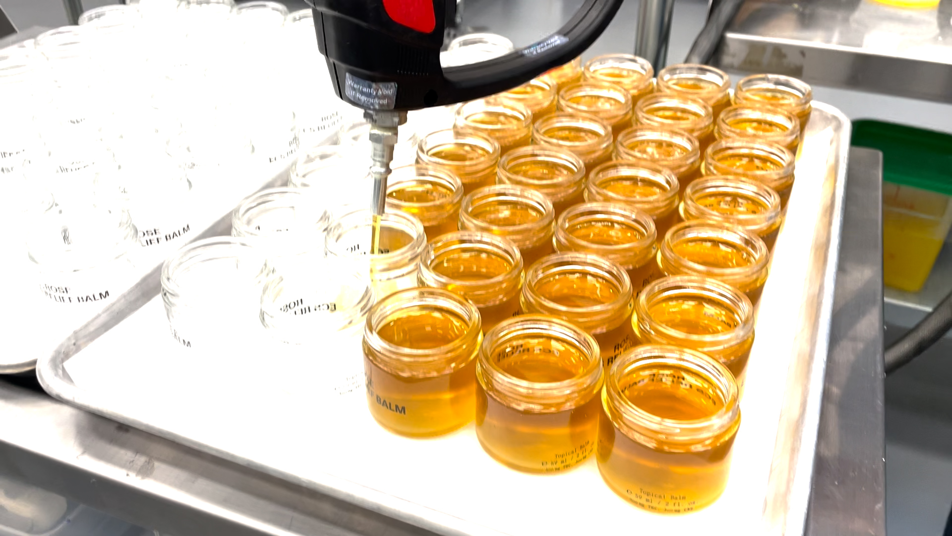 Small-batch herbal balm jars being filled on a production tray
